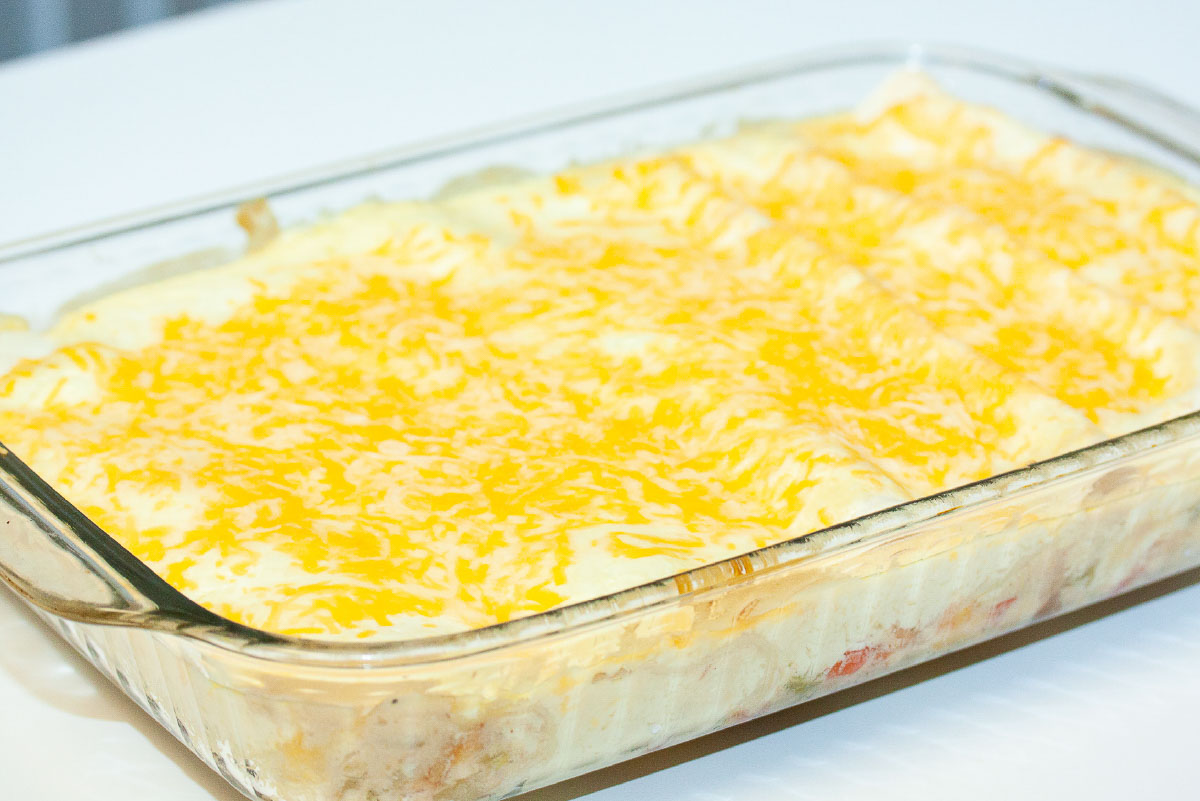 Pan of creamy white enchiladas topped with melted shredded cheese