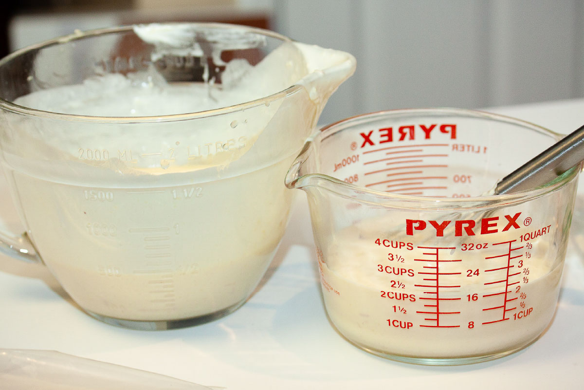 Batter bowl of white sauce for enchiladas separated into two parts; one half is in a measuring cup and the other is in the batter bowl