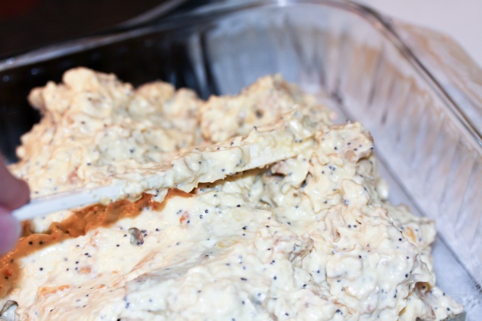 Spreading poppy seed chicken mixture in pan