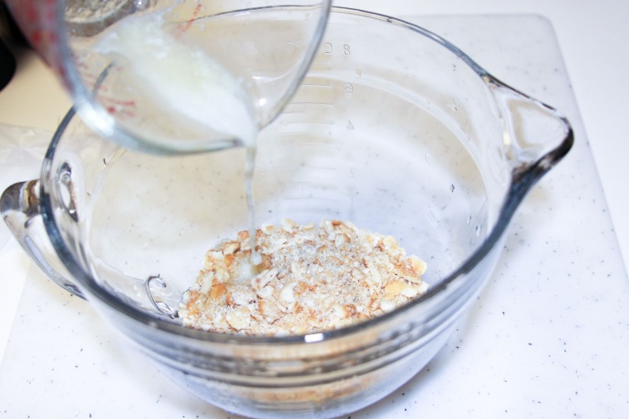 Mixing crushed crackers with melted butter