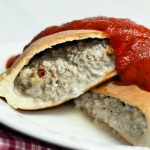 baked calzones with ground turkey and cheese filling and topped with marinara