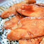 Chicken breasts glazed with French dressing, on a bed of rice on a platter.