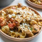 Bowl of shell pasta with tomatoes, feta cheese, and balsamic vinegar with text Mediterranean Chicken with Pasta