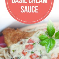 Breaded chicken breast covered with a cream sauce and resting on a plate of spaghetti. Text is Chicken in Basil Cream Sauce - Add Salt & Serve logo