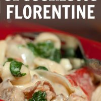 Red square bowl with orecchiette pasta, sliced onion, chopped bacon, roasted bell peppers, cooked spinach, and Alfredo sauce. There is a fork in the bowl. Text Easy Orecchiette Florentine Add Salt & Serve formerly menus4moms