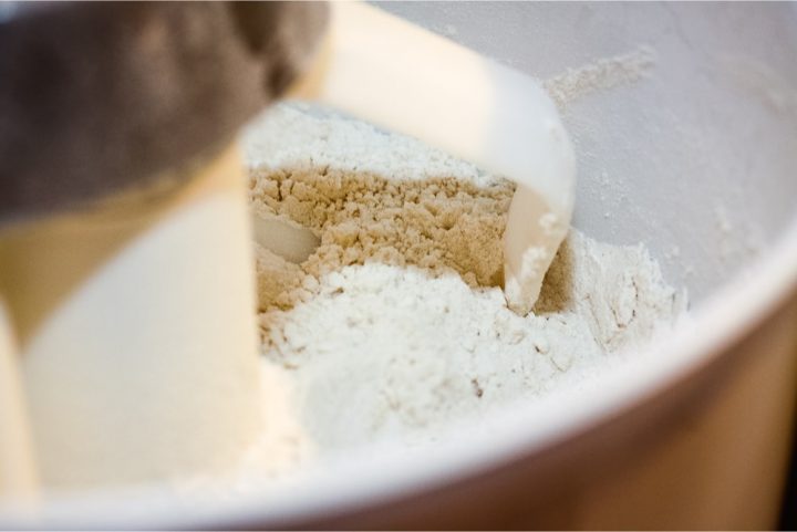 Stand mixer with dough paddles showing flour cut with butter to a cornmeal consistency
