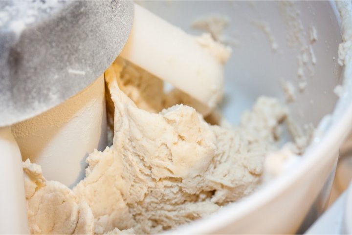 Stand mixer with dough paddles and biscuit dough being mixed
