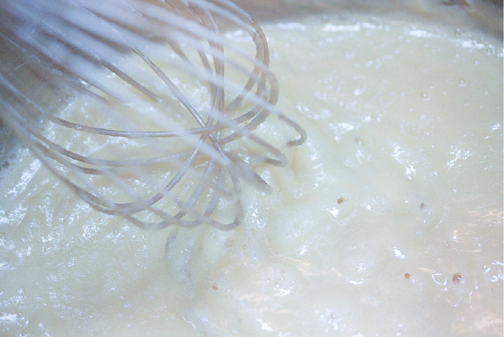A whisk and a bowl of baked potato soup.
