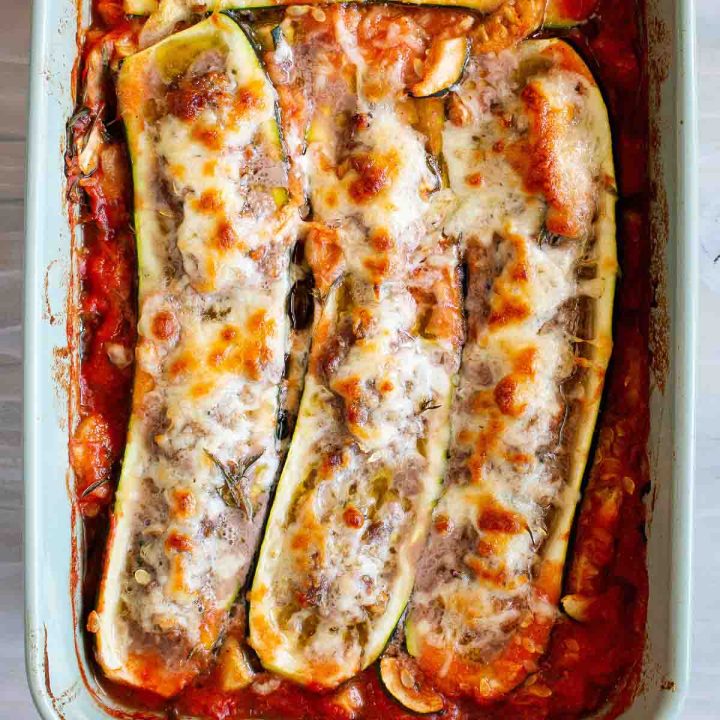 Zucchini Boats in a baking dish in a tomato sauce.