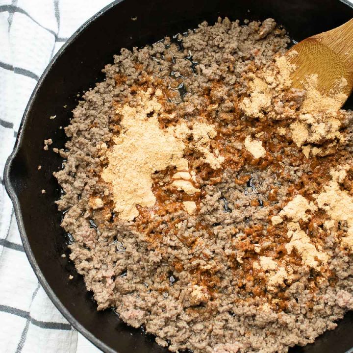 Overhead shot of ground beef in a cast iron skillet with taco seasoning on top