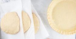 Overhead image of unbaked pie crust in a pie pan to the right and thick circles of pie crust dough stacked with parchment paper in between ready for the freezer