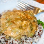 Chicken with chili cream sauce on a bed of rice on a white plate. There is a fork at the top of the plate.