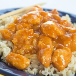 Crockpot Orange Chicken on a bed of rice with chopsticks
