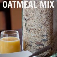 Oatmeal in a white bowl with spoon, glass of orange juice, jar of homemade instant oatmeal mix and text "Homemade Oatmeal Mix"