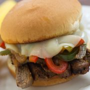 Close up photo of Steak Sandwich with Cheese and Peppers on a white plate