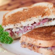 Two Reuben sandwiches on a white plate.