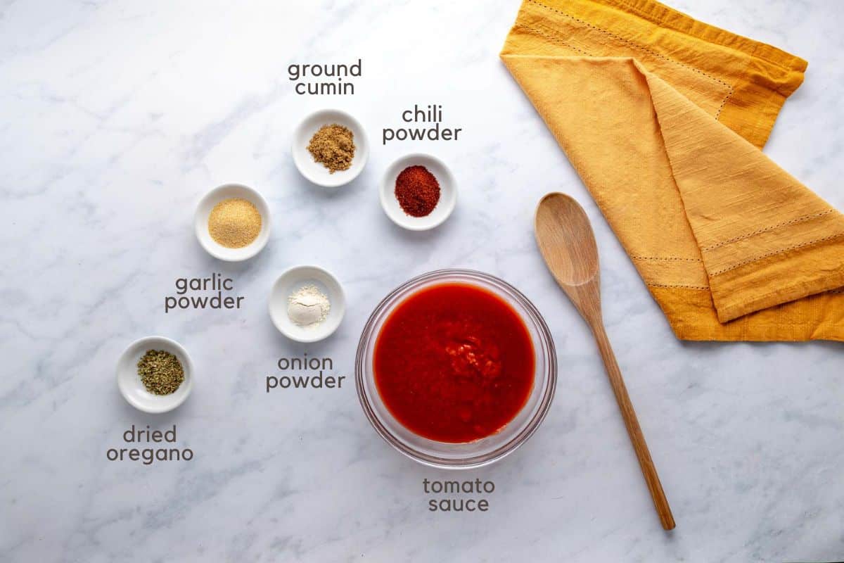 Ingredients for homemade red enchilada sauce: tomato sauce, chili powder, ground cumin, onion powder, garlic powder, and dried oregano.