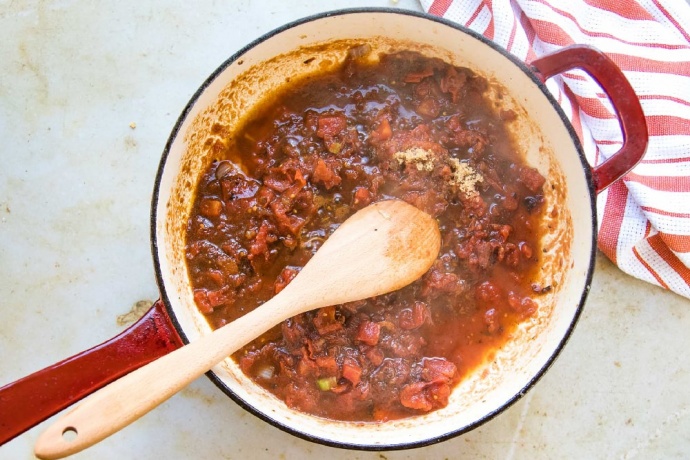 Cooked Worcestershire sauce and tomato mixture in a red and white skillet. There is a red and white striped dish towel beside the skillet.