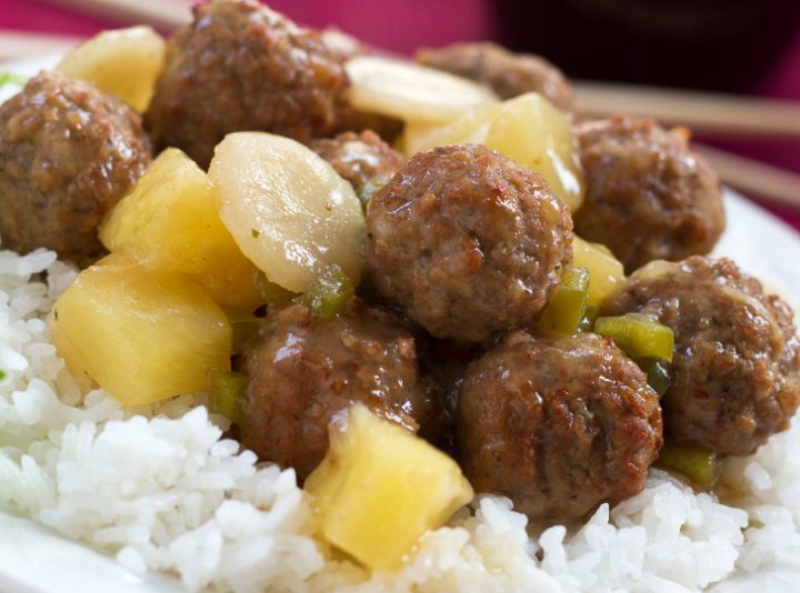 Meatballs, water chestnuts, and pineapple chunks in sauce over white rice, text Sweet and Sour Meatballs #quickandeasy