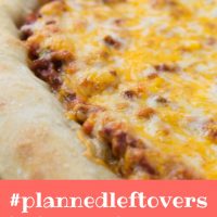 Side view of a whole pizza with sloppy joe sauce covered with colby-jack cheese on a thick crust and text Sloppy Joe Pizza #plannedleftovers Add Salt & Serve