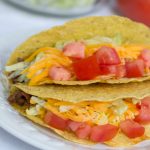 Tacos with shredded lettuce, grated cheese, and chopped tomatoes