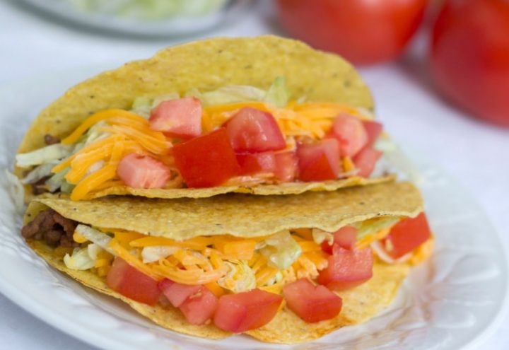Tacos with shredded lettuce, grated cheese, and chopped tomatoes