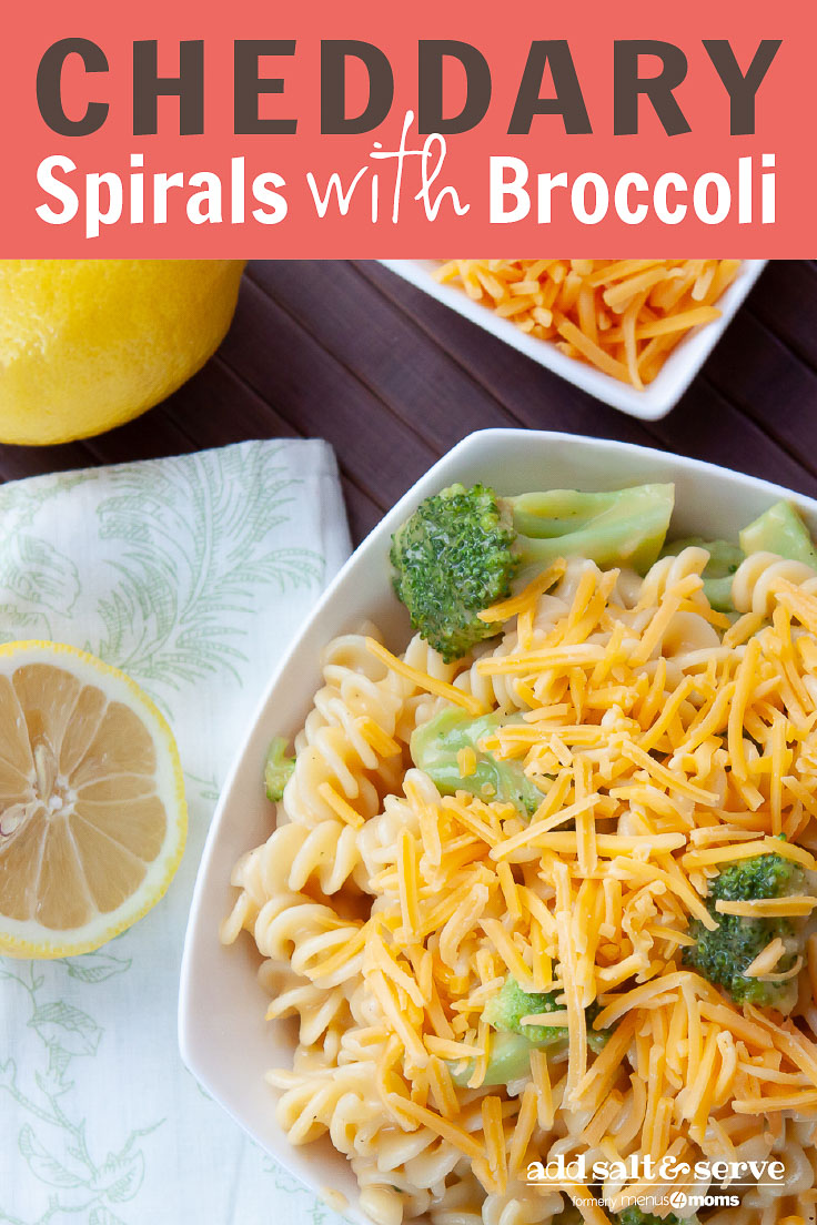 White bowl with rotini pasta, broccoli, and shredded cheddar cheese, next to lemons and a bowl of shredded cheese; text is Cheddary Spirals with Broccoli - Add Salt & Serve logo