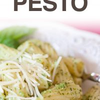 Rigatoni on a white plate topped with pesto and shredded parmesan cheese. Text Homemade Pesto Add Salt & Serve formerly menus4moms