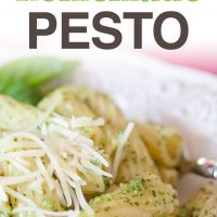 Rigatoni on a white plate topped with shredded parmesan cheese and pesto. Text Pasta with Homemade Pesto Add Salt & Serve formerly menus4moms