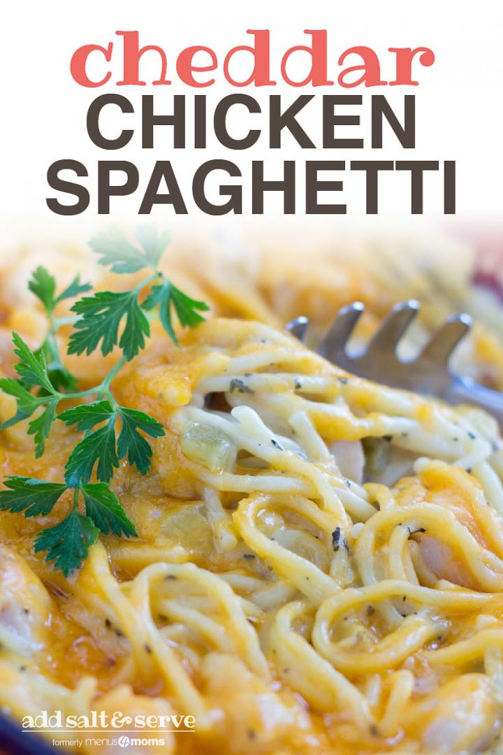Pasta server pulling out a serving of a casserole of spaghetti and chicken in a white sauce topped with cheddar cheese and garnished with parsley