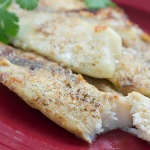 Tilapia fillets on a red plate garnished with parsley