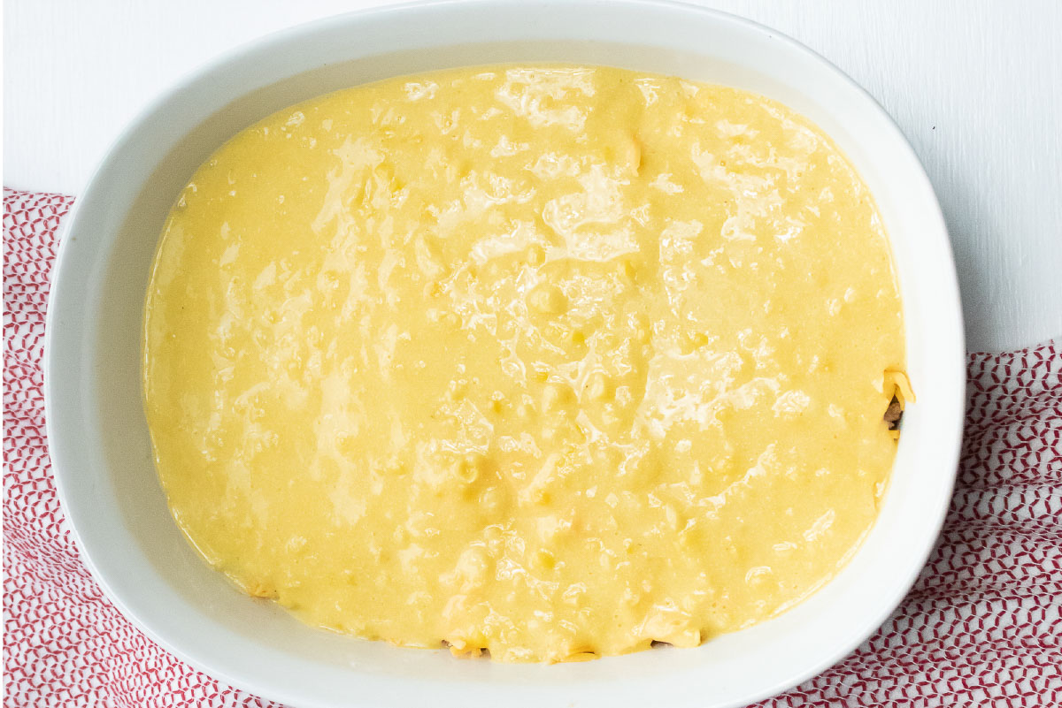 White casserole dish with a topping of cornbread batter