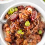 Spoonful of beef and beans garnished with green onion.