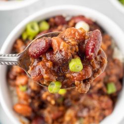 Spoonful of beef and beans garnished with green onion.