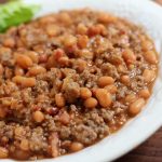 Bowl of cooked ground beef and pinto beans in sauce with text Beef With Beans Menus4Moms