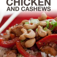 Red plate with chopsticks and rice, sliced red bell peppers, cashews, chicken, and green onions