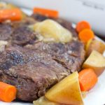 Roast beef with chopped carrots and potatoes on a white plate