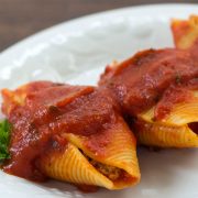 White plate with 3 jumbo pasta shells stuffed with beef and covered with spaghetti sauce, garnished with parsley