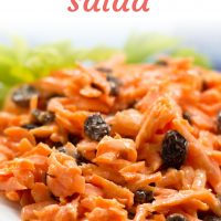 Carrot Raisin Salad on a white plate garnished with celery leaves and text Carrot Raisin Salad Add Salt & Serve
