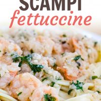 White plate with shrimp, minced garlic, and parsley on a bed of fettuccine