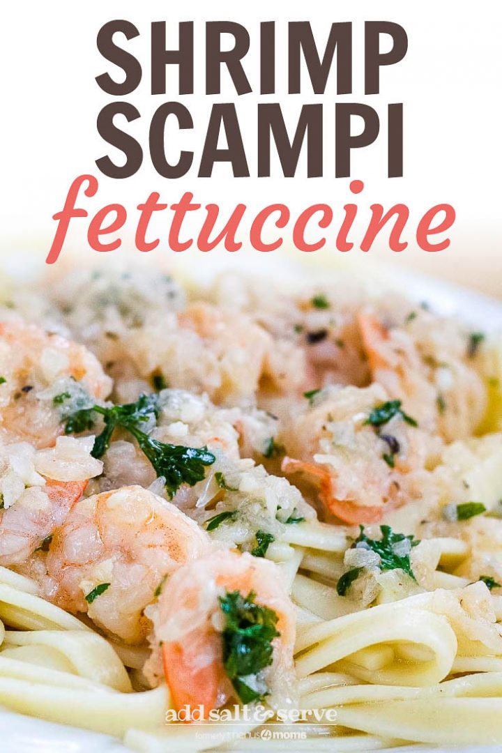 White plate with shrimp, minced garlic, and parsley on a bed of fettuccine