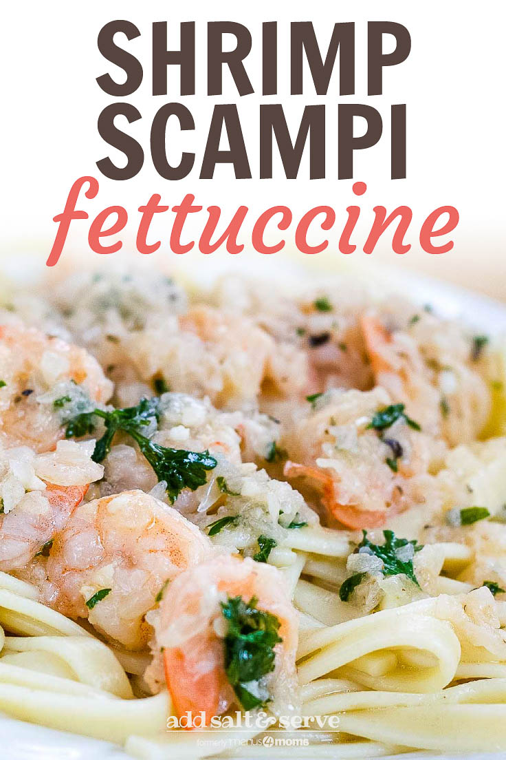 White plate with shrimp, minced garlic, and parsley on a bed of fettuccine