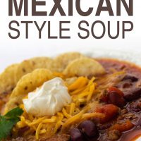 White bowl filled with soup of beans, tomatoes, and beef, topped with shredded cheddar cheese, tortilla chips, and sour cream, garnished with cilantro; text quick and easy mexican style soup Add Salt & Serve formerly Menus4Moms