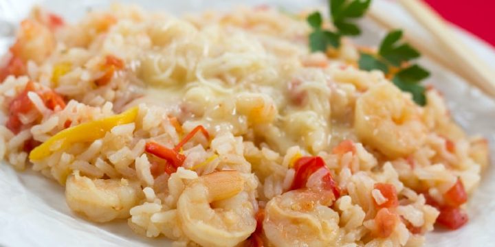 White plate with rice, shrimp, diced tomatoes, and strips of bell peppers, with melted Monterey Jack cheese on top.