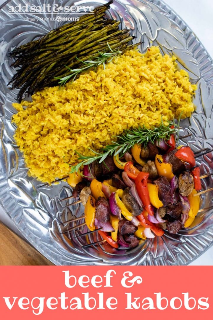 Large pewter platter of yellow rice, grilled asparagus, and grilled beef kabobs with bell peppers, red onions, and mushrooms with text Beef & vegetable kabobs Add Salt & Serve
