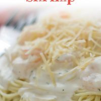 Angel hair pasta with alfredo sauce and shrimp, topped with shredded parmesan cheese, on a white plate. Text creamy garlic shrimp add salt & serve formerly menus4moms