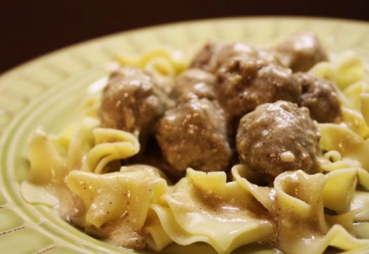 Yellow bowl with egg noodles covered in meatballs with cream sauce