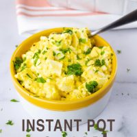 Prepared egg salad garnished with chopped parsley in a white bowl with a yellow rim with whole wheat rolls in the background and text Instant Pot no-peel egg salad