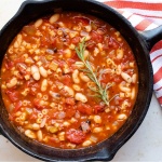 Cast iron skillet with Pasta e Fagioli, a soup made with pasta,tomatoes, chopped celery and onion, cannellini beans, and tomato sauce.