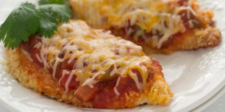 Two chicken breasts coated with cracker crumbs, and topped with salsa and melted shredded cheese, on a white plate.